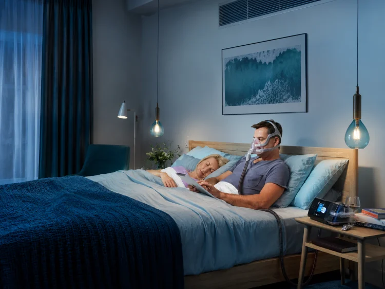 terapia cpap mężczyzna w łóżku z maska i aparatem.png